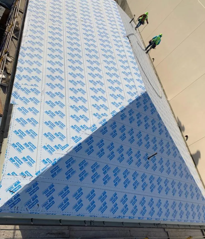 Professional roofers installing underlayment on a metal roof in Warsaw